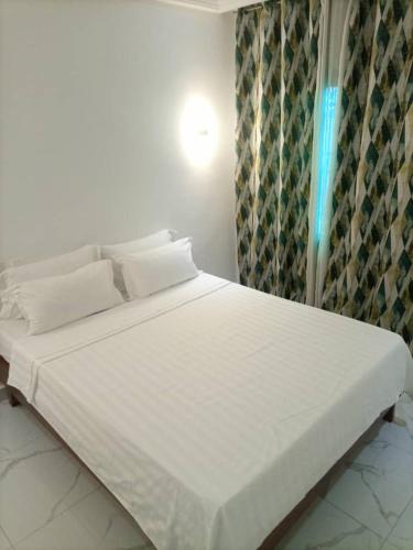 a bed with white sheets and pillows in a room at appartement 2 crepin in Pointe-Noire