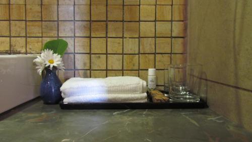 a bathroom counter with towels and a vase with a flower at Mountain Retreat Kodai in Kodaikānāl