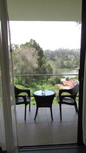 a balcony with a table and two chairs and a window at Mountain Retreat Kodai in Kodaikānāl