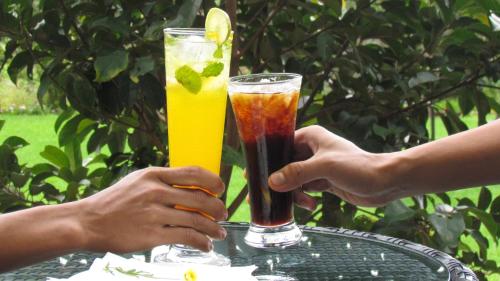 two people holding up two drinks on a table at Mountain Retreat Kodai in Kodaikānāl