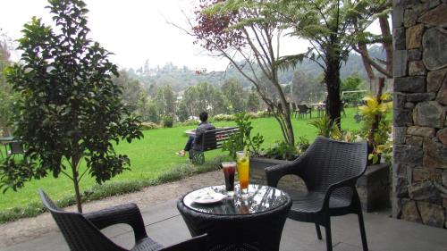 a table with chairs and a man sitting on a bench at Mountain Retreat Kodai in Kodaikānāl