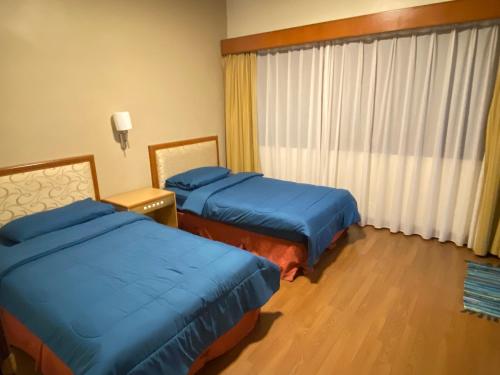 um quarto de hotel com duas camas e uma janela em COZY HOME COPTHONE RESORT em Brinchang