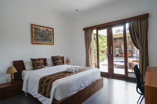 een slaapkamer met een bed en een glazen schuifdeur bij D'Meten Guest House Canggu in Canggu