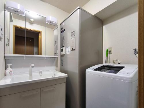 a bathroom with a sink and a washing machine at Ostay Kitahama Hotel Apartment in Osaka