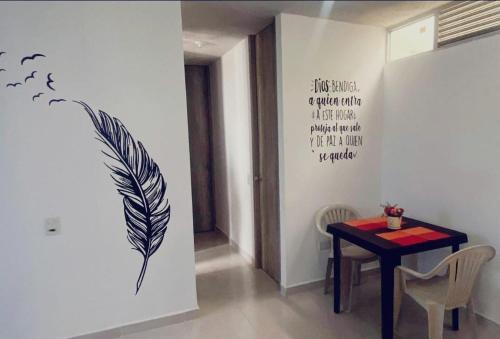 Apartamento Amoblado Cartagena في كارتاهينا دي اندياس: غرفة طعام مع طاولة وريشة على الحائط