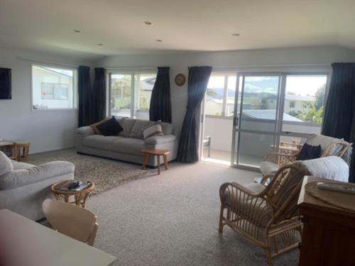 a living room with a couch and a table and chairs at Hosts on the Coast Catch of the Day in Cooks Beach