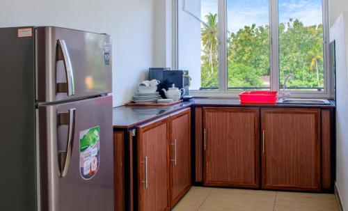 een keuken met een roestvrijstalen koelkast en houten kasten bij Pavulak in Weligama