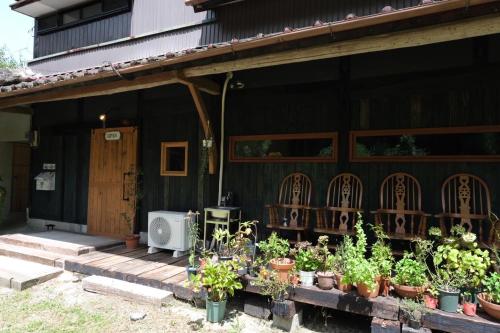 a porch of a house with a bunch of plants at hostel+cafe たね 