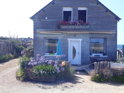 a small house with flowers in front of it at Gîte Les Chardons Bleus , les pieds dans l’eau in Pleubian