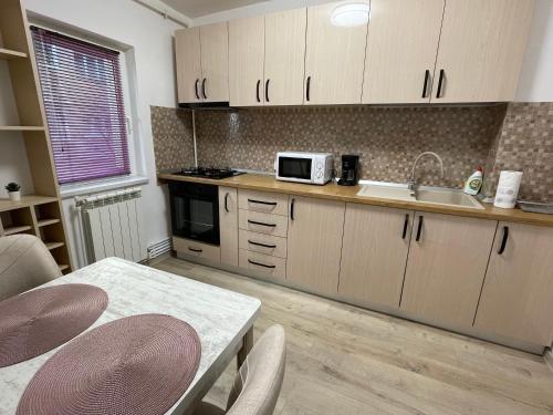 uma cozinha com um lavatório e uma mesa com cadeiras em Grove Apartment em Buzau
