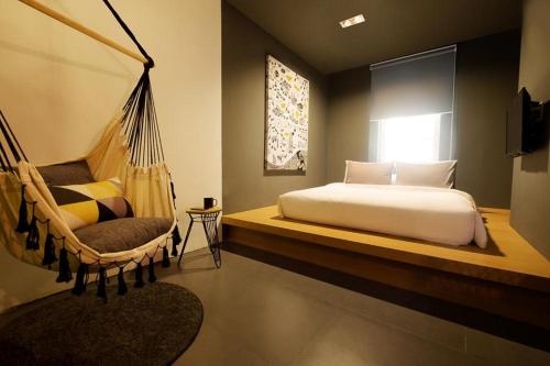 1 dormitorio con hamaca, 1 cama y ventana en The Hammock Hotel Ben Thanh, en Ho Chi Minh