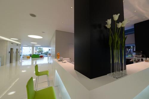 a lobby with a vase of flowers and green chairs at Giulivo Hotel & Village in Baia Domizia