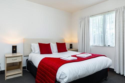 a bedroom with a large bed with red pillows at Jasmine Court Motel in Picton