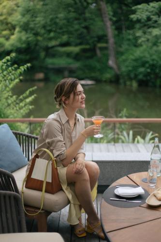 a woman sitting on a chair holding a drink at Four Seasons Hotel Kyoto in Kyoto