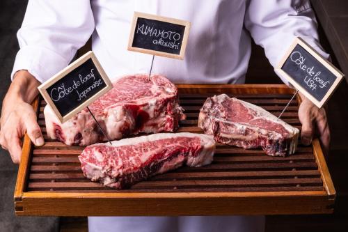 a man holding a grill with different types of meat at Four Seasons Hotel Kyoto in Kyoto
