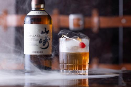 a bottle of whisky and a glass with a cherry on it at Four Seasons Hotel Kyoto in Kyoto