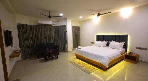 a bedroom with a large white bed and a chair at Hotel TamilNadu, Kancheepuram in Kanchipuram