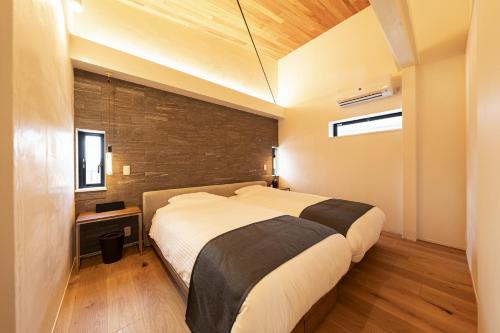 a bedroom with a large bed and a brick wall at UNITED HILLS GARDEN in Fushiochō