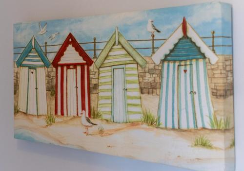 a painting of four beach huts on the sand at Tegeirian in Porthcawl
