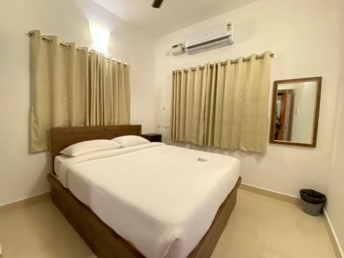 1 dormitorio con cama blanca y espejo en Le Poshe Suite en Pondicherry