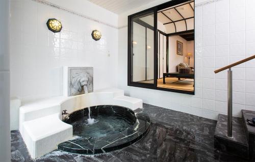 La salle de bains est pourvue d'une baignoire avec un lavabo et un miroir. dans l'établissement Bettei Soan, à Minami Aso