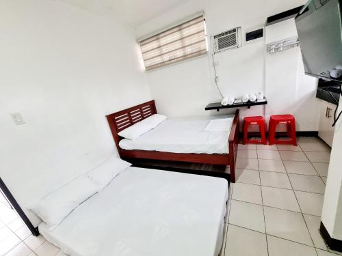 a room with two beds and two red chairs at Dasma Lofts Hotel near Dela Salle Dasma in Dasmariñas