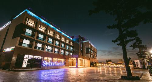 a building with a sign in front of it at night at Hotel Sweet Castle Jeju Hamdeok in Jeju