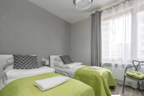 1 Schlafzimmer mit 2 Betten mit grüner Bettwäsche und einem Fenster in der Unterkunft Close to Chopin airport, free parking in Warschau