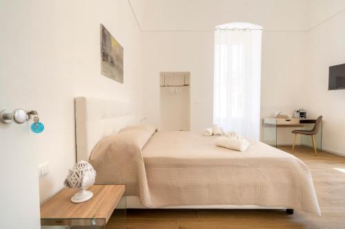 a white bedroom with a bed and a table at Casa Del Barone - Luxury Suites in Monopoli