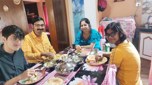 a group of people sitting around a table eating food at Lotus Homestay in Darjeeling