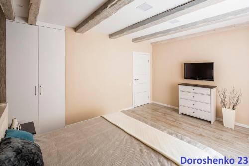 a bedroom with a large bed and a tv at Do Lvova Central Apartments in Lviv