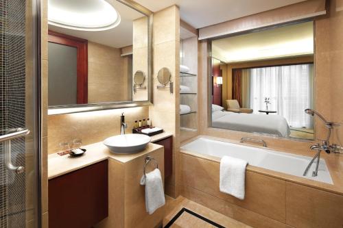 a bathroom with a tub and a sink and a mirror at Sheraton Shenzhen Futian Hotel in Shenzhen