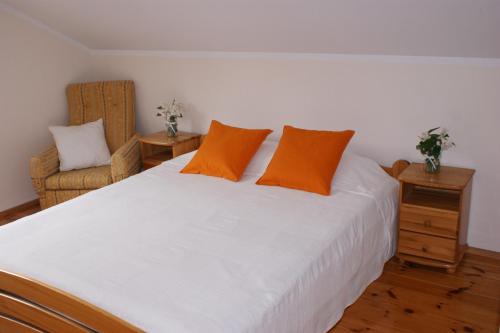 ein Schlafzimmer mit einem großen weißen Bett mit orangefarbenen Kissen in der Unterkunft Wypoczynek na Kurpiach in Kadzidło