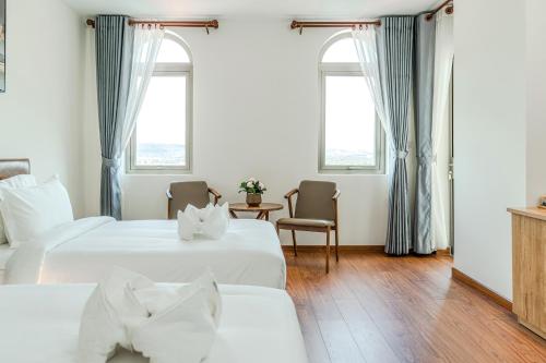 a hotel room with two beds and two windows at Sea Breeze Hotel & Villa in Sihanoukville