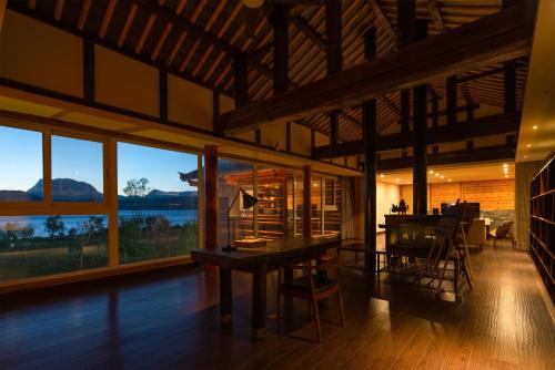 a dining room with a table and some windows at Slow Living Villa in Ninglang