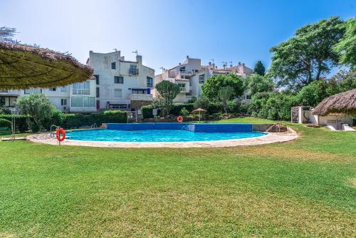 a swimming pool in a yard with a building in the background at Golden Bay Apartment in Estepona