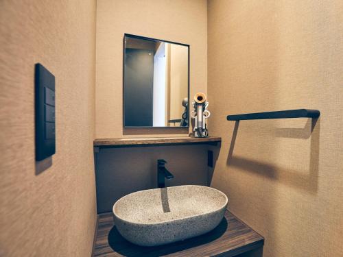 a bathroom with a stone sink and a mirror at ルクス箱根湯本 LUX HAKONE YUMOTO in Hakone