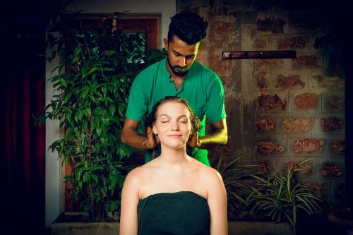 a woman getting her hair cut by a man at Sath Villa Naadi Ayurveda Resort in Moragalla