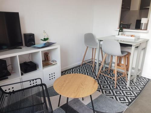 a living room with two chairs and a table and a tv at Appartement Liza 2 pièces Vue Mer à Cabourg in Cabourg