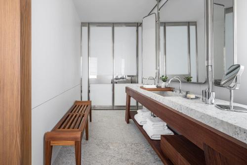 a bathroom with a sink and a bench and mirrors at R48 Hotel and Garden in Tel Aviv