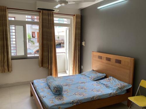 um quarto com uma cama com lençóis azuis e uma janela em KEIRA s HOUSE em Ho Chi Minh