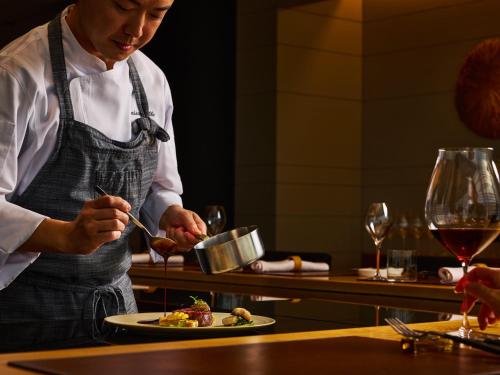 a chef preparing a plate of food in a restaurant at ANA InterContinental Beppu Resort & Spa by IHG in Beppu