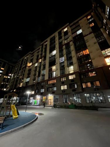 a large apartment building at night with a yellow slide at Aylin apartments 359/3 in Almaty