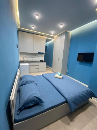 a blue bedroom with a bed and a kitchen at Aylin apartments 359/3 in Almaty