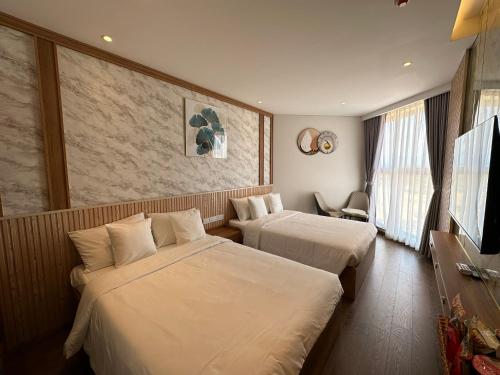 a hotel room with two beds and a television at Apec mandala Mũi Né in Ấp Khánh Phước (1)