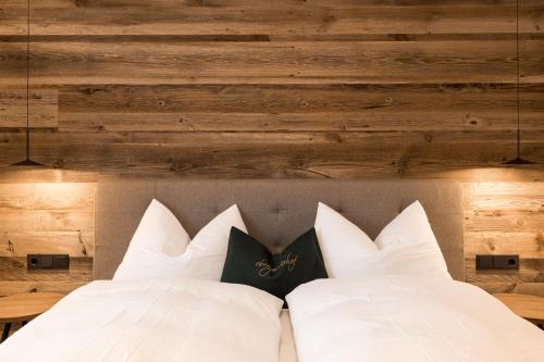 a bed with white pillows in a room with wooden walls at Obergasserhof Apt Waldruhe in Riscone