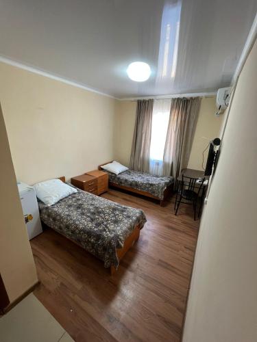 a room with two beds and a table in it at Гостиница Набережная in Balqash