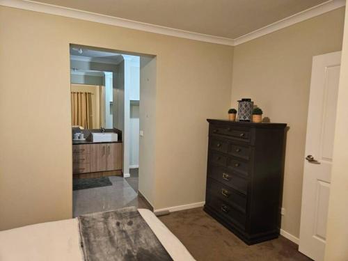 a bedroom with a bed and a dresser and a mirror at Tranquil home in Point Cook. in Point Cook