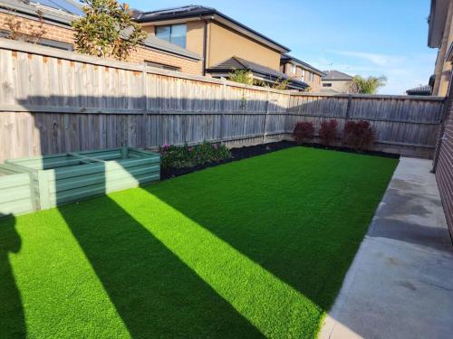 a backyard with a fence and a green lawn at Tranquil home in Point Cook. in Point Cook