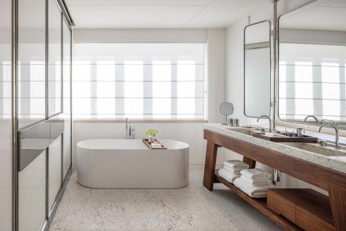 a bathroom with a tub and a large mirror at R48 Hotel and Garden in Tel Aviv